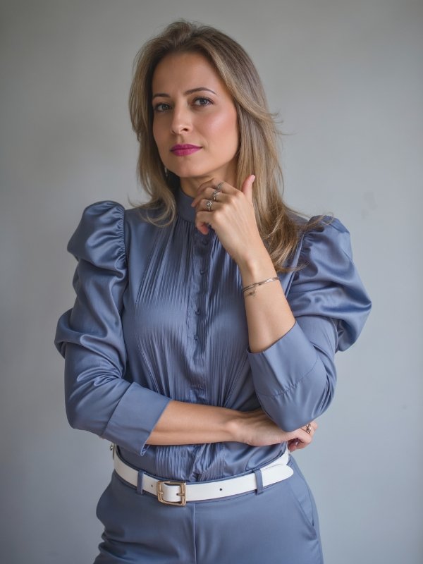 Márcia Schenatto, de blusa cinza-azulada, olhando para a câmera.
